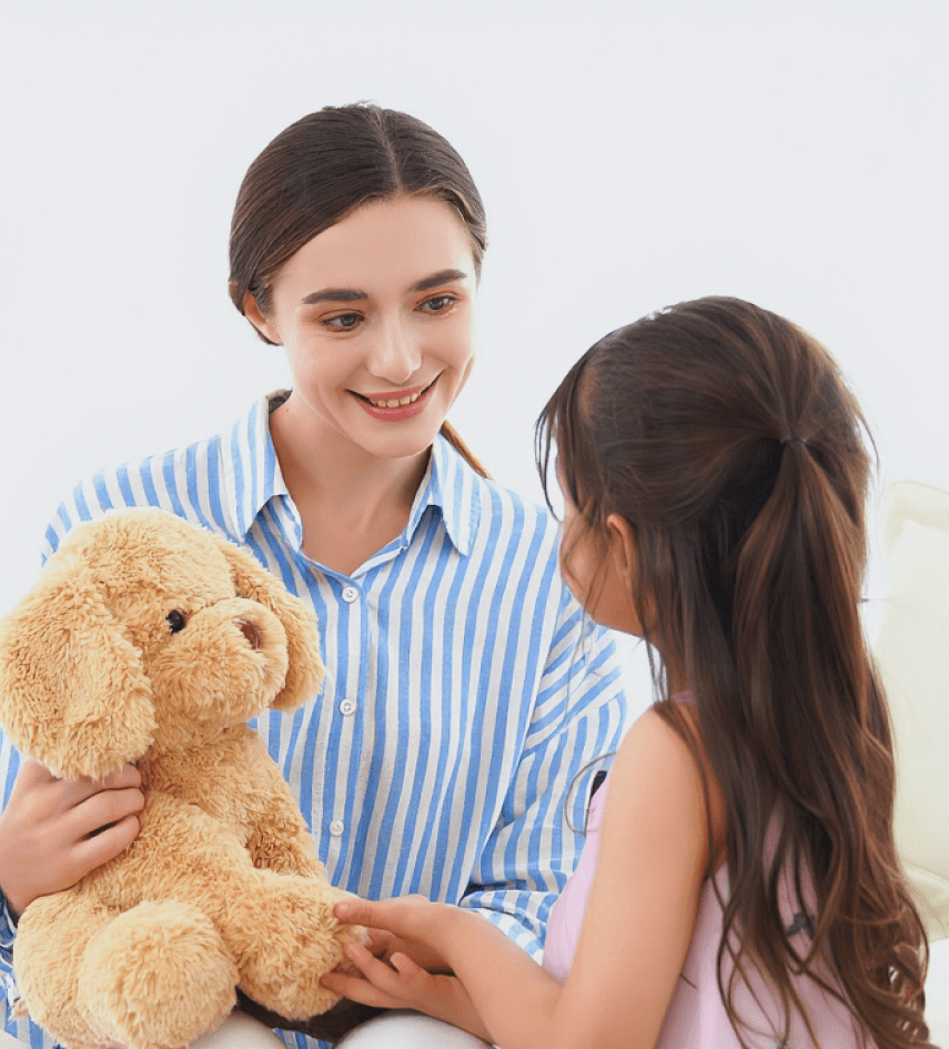 Woman holding AI plush toy dog interacting with a young girl on a light background