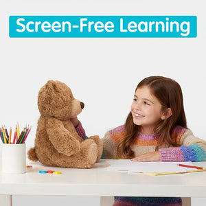Young girl sitting at a table with TalkiPal's AI plush bear toy, smiling and engaged in an activity.