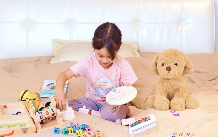 Child playing with toys on a bed next to a teddy bear AI toy